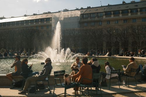 Free A lively scene of people relaxing around a fountain in Paris during spring. Stock Photo