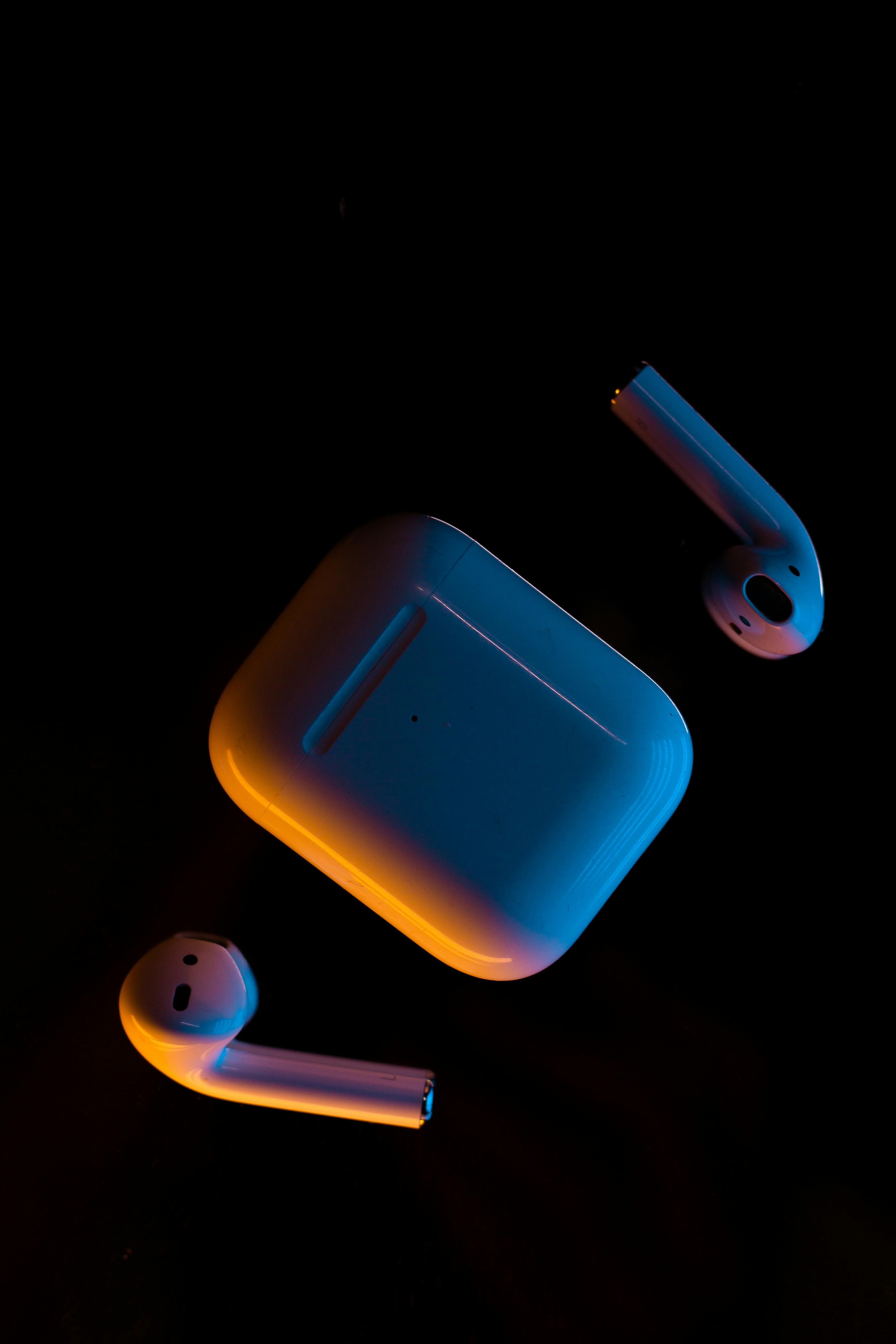 Kostenlos Moderne kabellose Ohrhörer und ihr Etui sind in ein warmes Licht getaucht und unterstreichen ihr elegantes Design. Stock-Foto