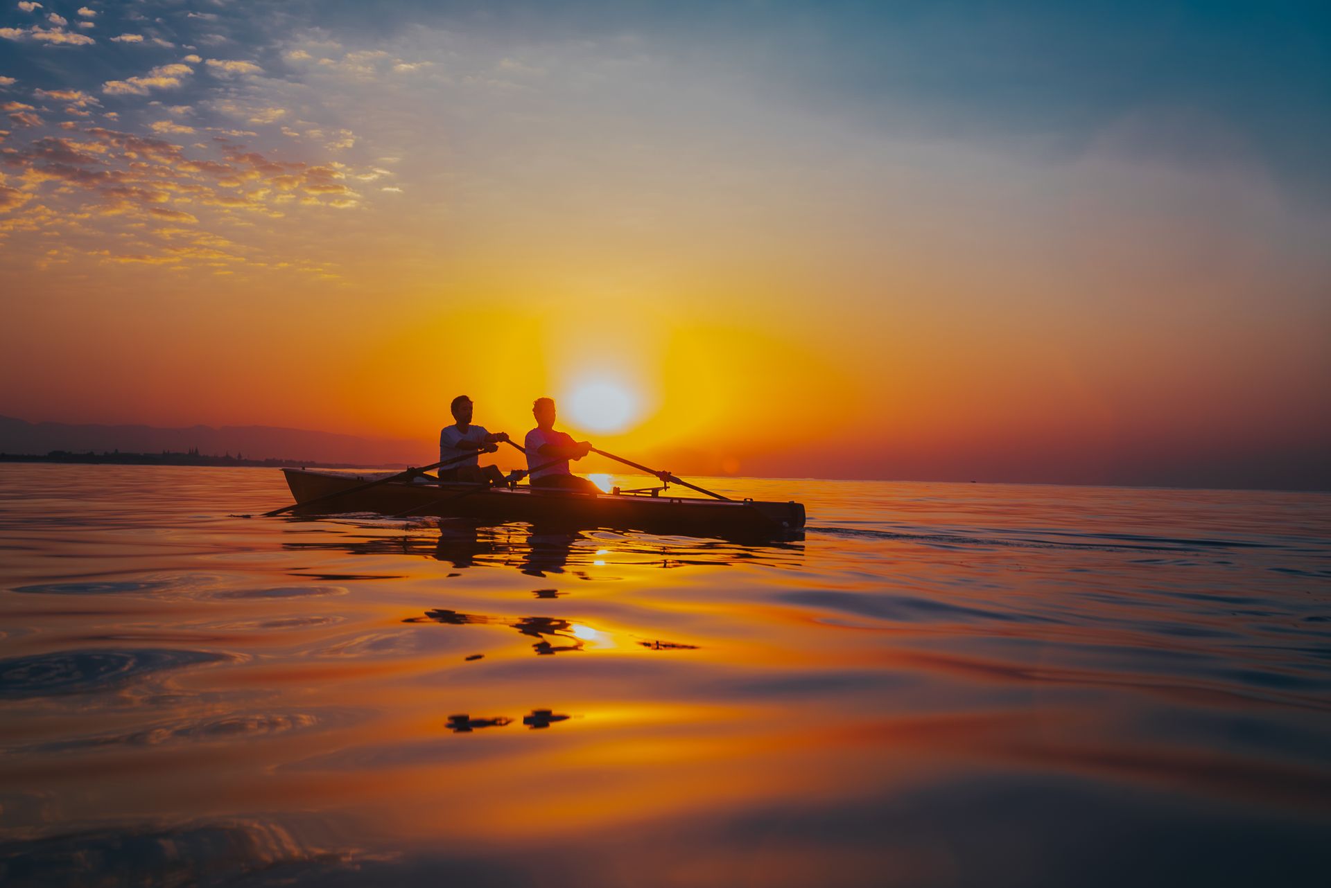 Two kayakers rowing on calm waters at sunset in Antalya, Türkiye, creating a serene silhouette.