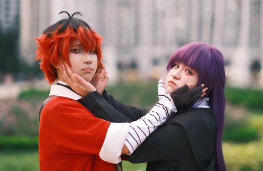 Colorful cosplay with red and purple wigs, captured outdoors.
