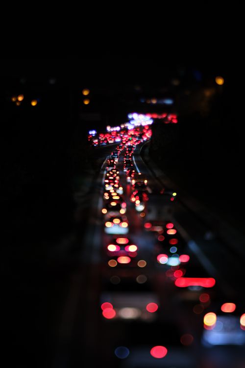 Free Blurred taillights of nighttime traffic creating a vibrant bokeh effect. Stock Photo