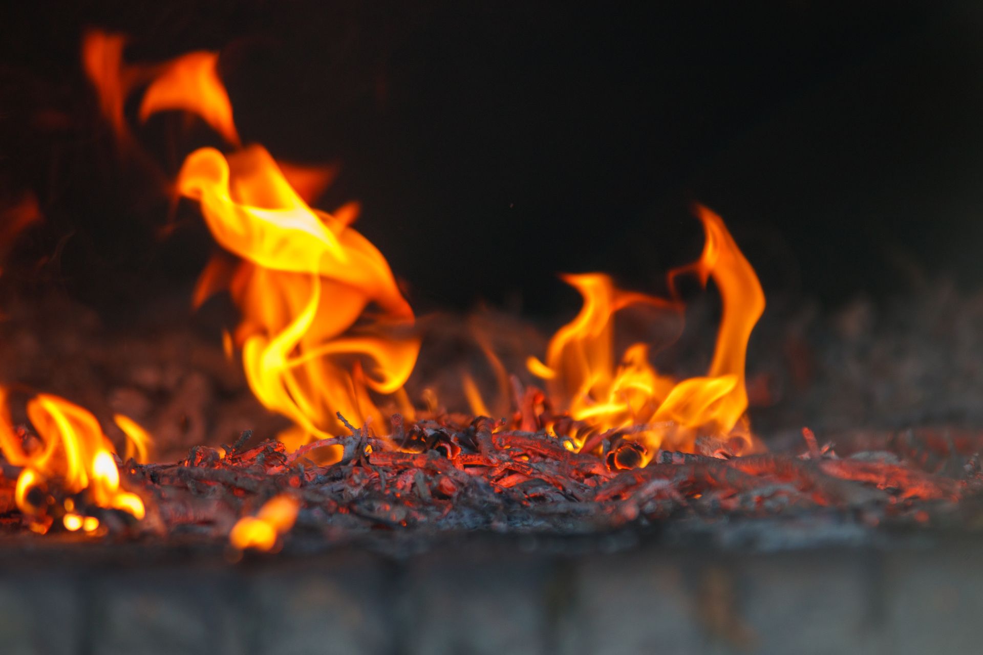 Intense close-up of vibrant flames and glowing embers in a fireplace.