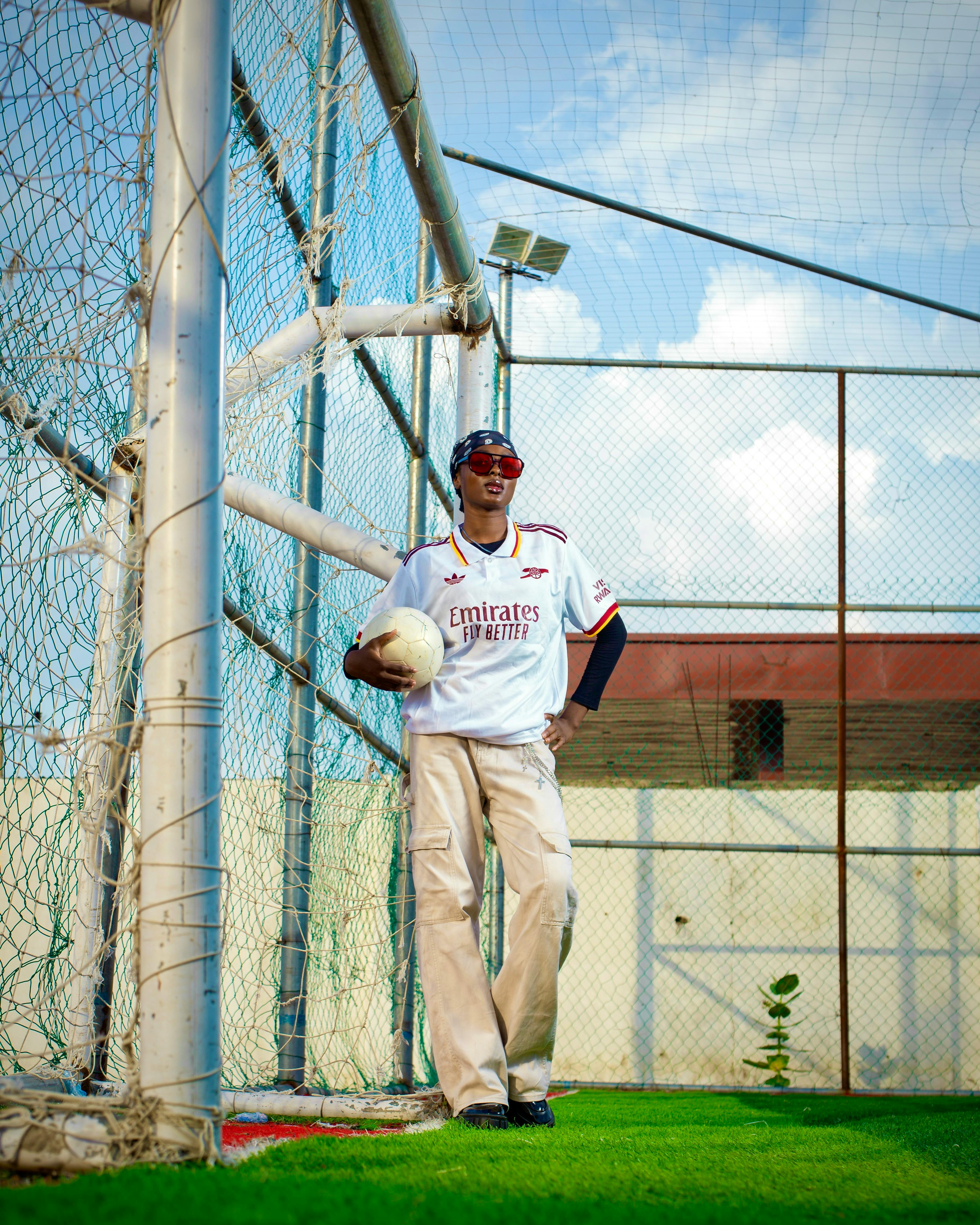 Young soccer player relaxing by the goalpost on a sunny day