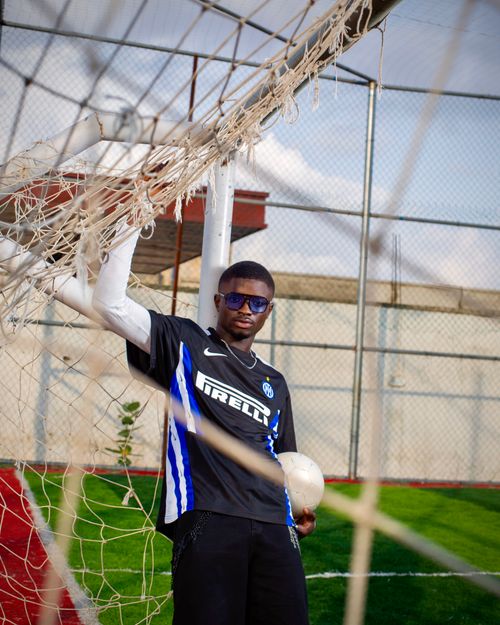 Free A young male footballer in sports attire posing confidently next to a goal on a sunny day. Stock Photo
