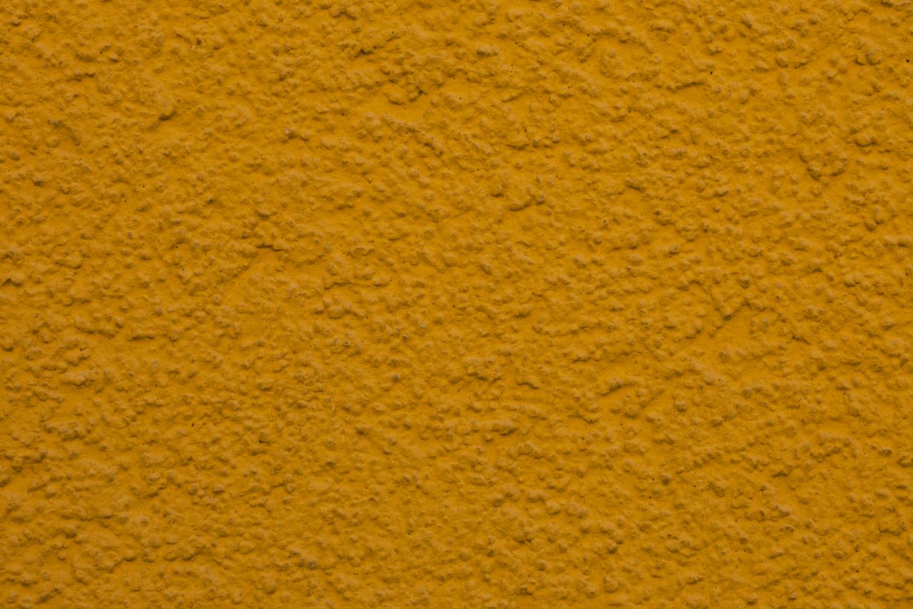 close up of a textured yellow plaster wall ideal for backgrounds or de