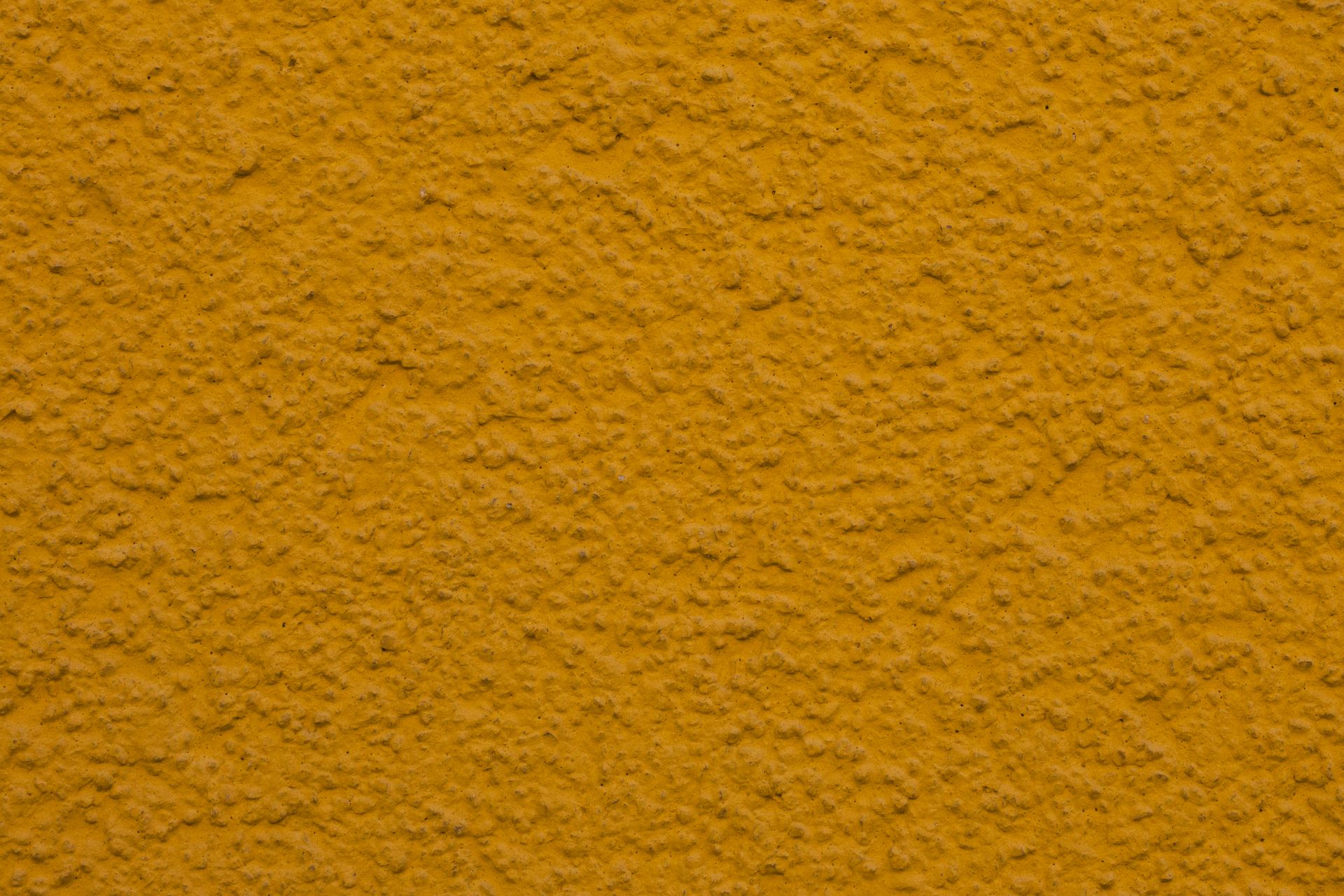 Close-up of a textured yellow plaster wall, ideal for backgrounds or design projects.