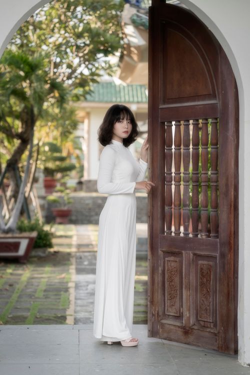 Woman in White Traditional Dress by Wooden Doorway · Free Stock Photo