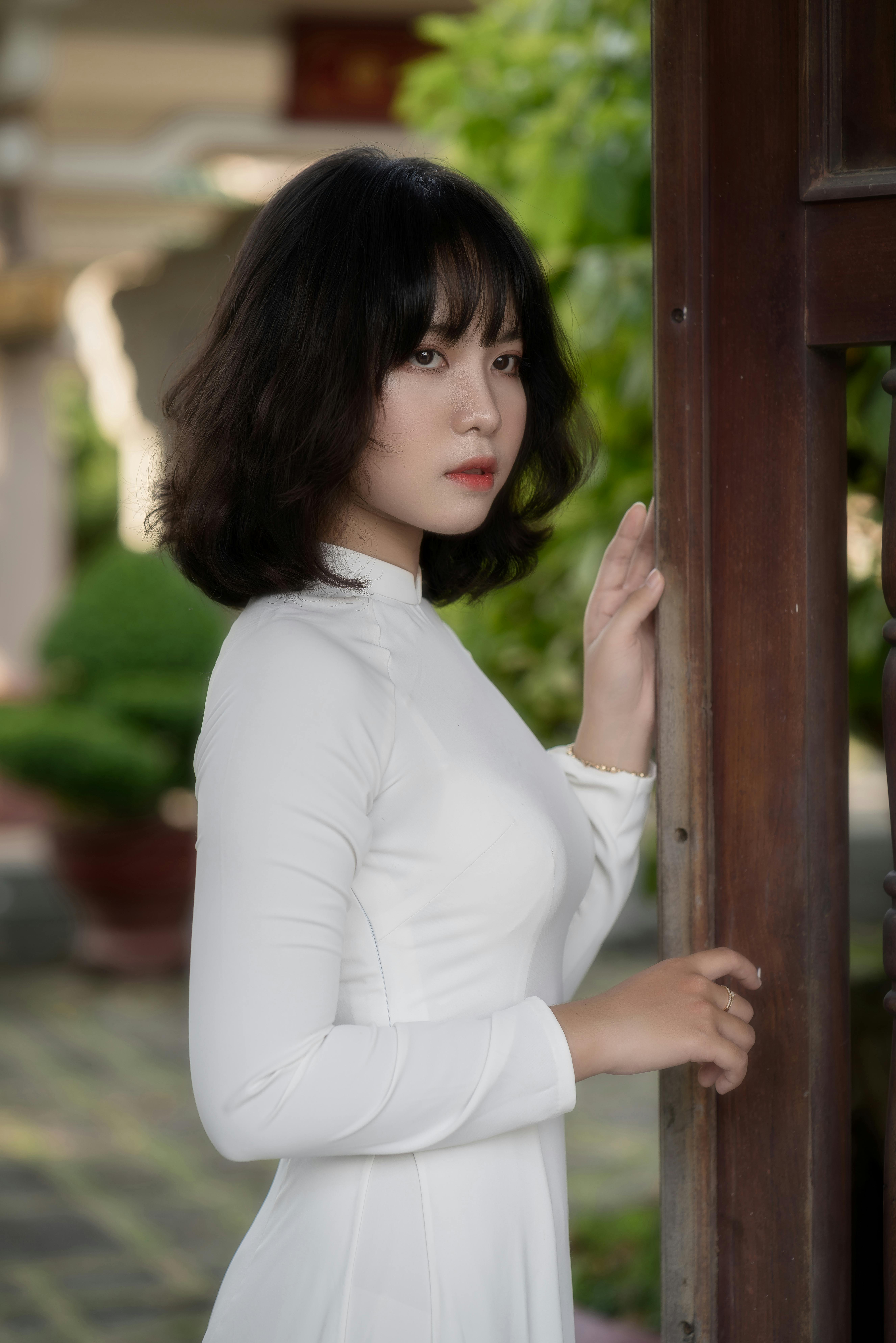 Serene portrait of a woman in a traditional white Ao Dai in an outdoor setting, exuding elegance.