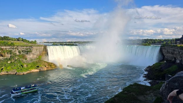 A breathtaking view of Niagara Falls with a tour boat navigating the river below the cascading waters.