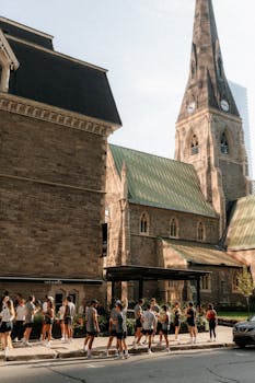 Street view of a historic church with a clock tower, bustling with people and urban life.