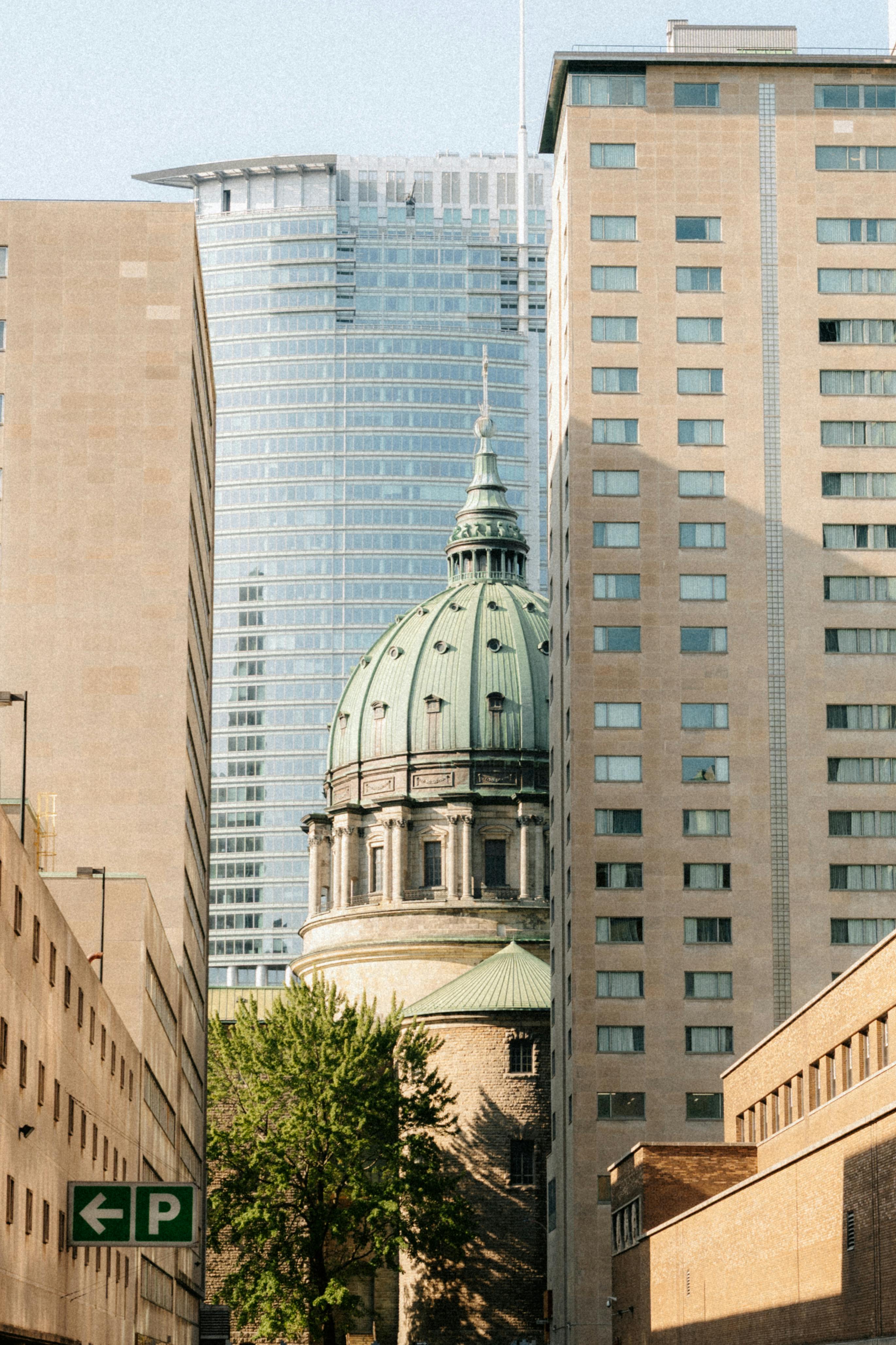 Stunning view of a historic dome nestled among modern skyscrapers in downtown Montréal, Québec, Canada.