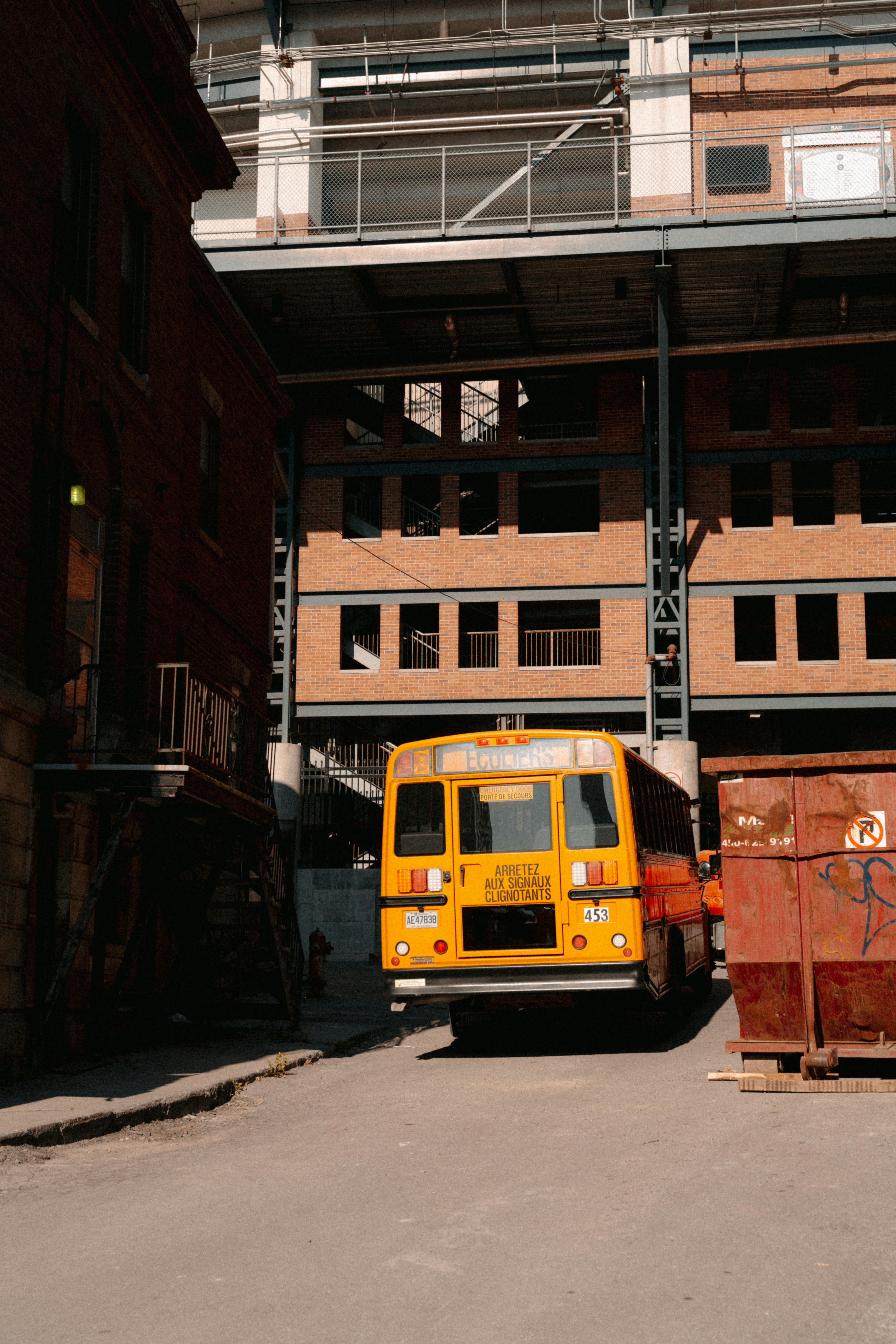 A yellow school bus parked in a gritty urban alleyway in Montreal, illustrating city life.