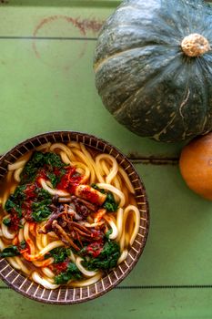 Warm udon noodle soup with spinach and kimchi, perfect for fall meals.