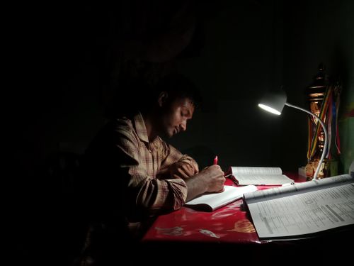 Free A young man intensely studies under a desk lamp, highlighting focus and determination. Stock Photo