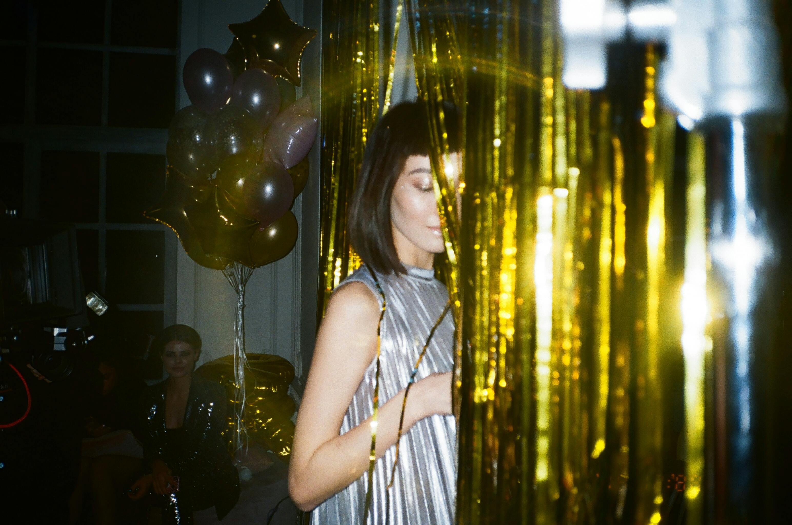 woman hiding behind gold foil curtain