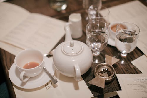 çaydanlıktan Neredeyse Boş çay Fincanı Ve Masa üstünde Cam Bardak İçme