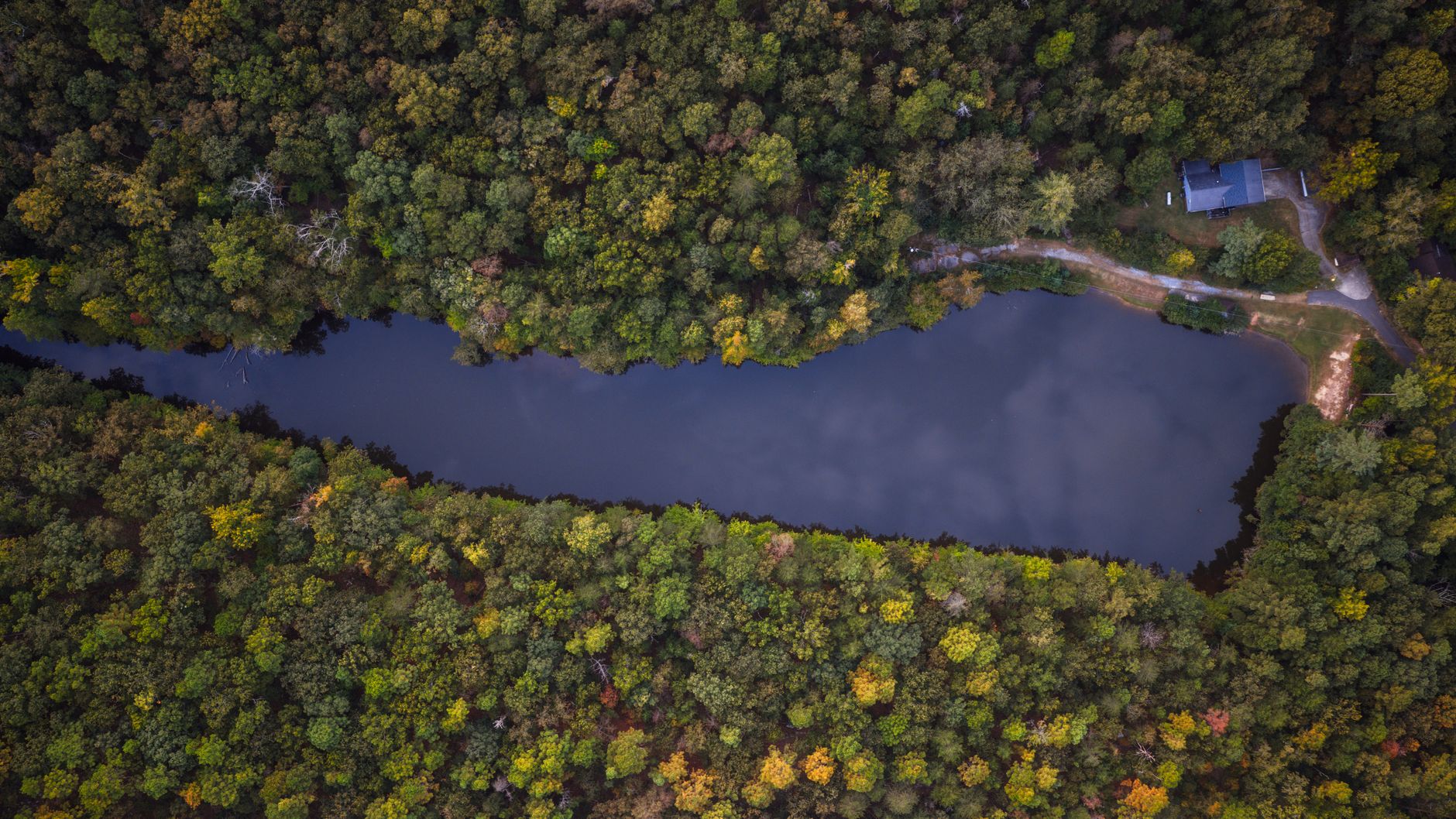 Aerial photograph showcasing rich autumn foliage surrounding a serene river in Pelham, Alabama.