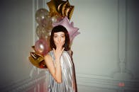 一位身穿节日服装、头戴气球的女子，正在室内欢快地庆祝