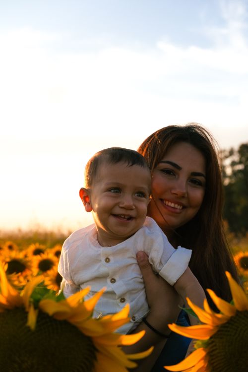 Free Mother and child enjoying a joyful moment in a vibrant sunflower field during sunset. Stock Photo