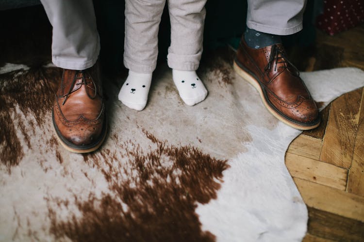 Child Wearing Socks Standing Between Person's Feet