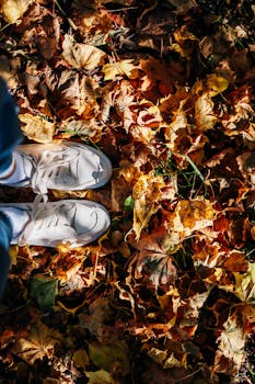 White sneakers on vibrant autumn leaves capturing the essence of fall outdoors.