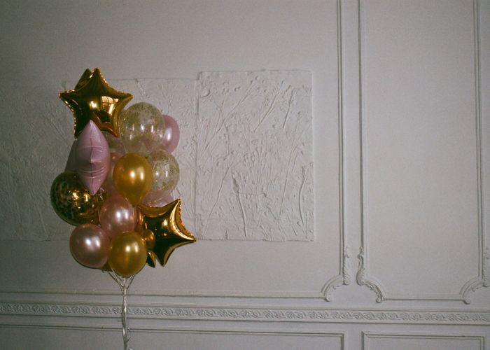 Gold and blush balloon cluster against a textured wall