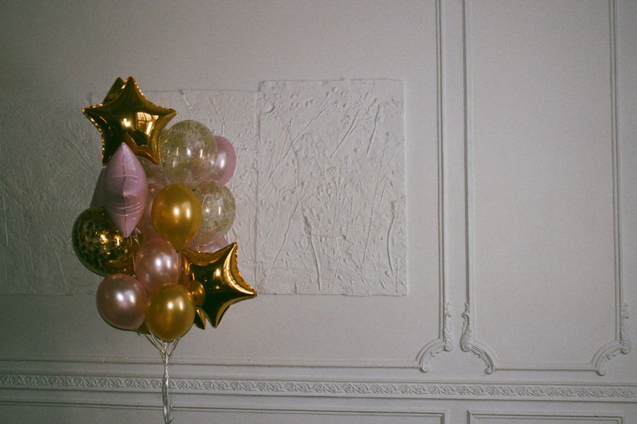 Gold and pink balloon installation against a textured wall