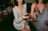 在一场时尚派对上，两名女子穿着优雅，举着鸡尾酒互相敬酒