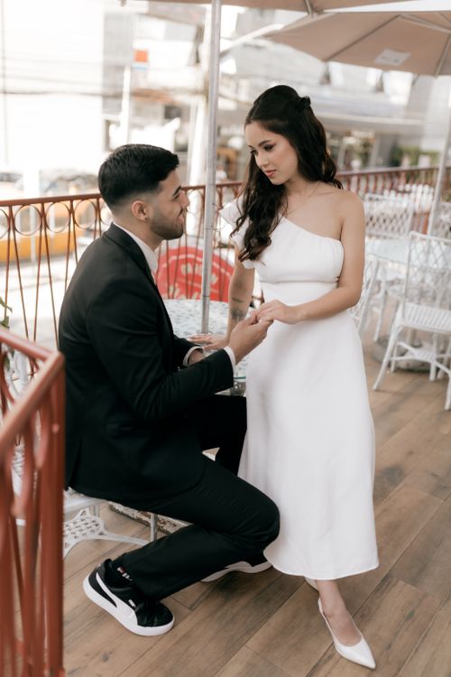 Free A couple dressed formally enjoys an intimate moment on a stylish balcony. Stock Photo