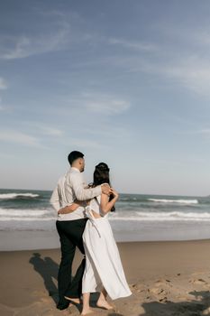 A couple enjoys a romantic walk on the beach under the clear blue sky.