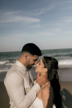 A couple shares an intimate moment by the ocean on a sunny day, capturing love and warmth.