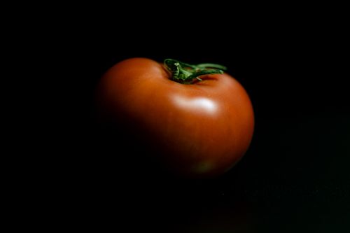 Free Detailed close-up of a ripe tomato with dark lighting, emphasizing its natural texture. Stock Photo