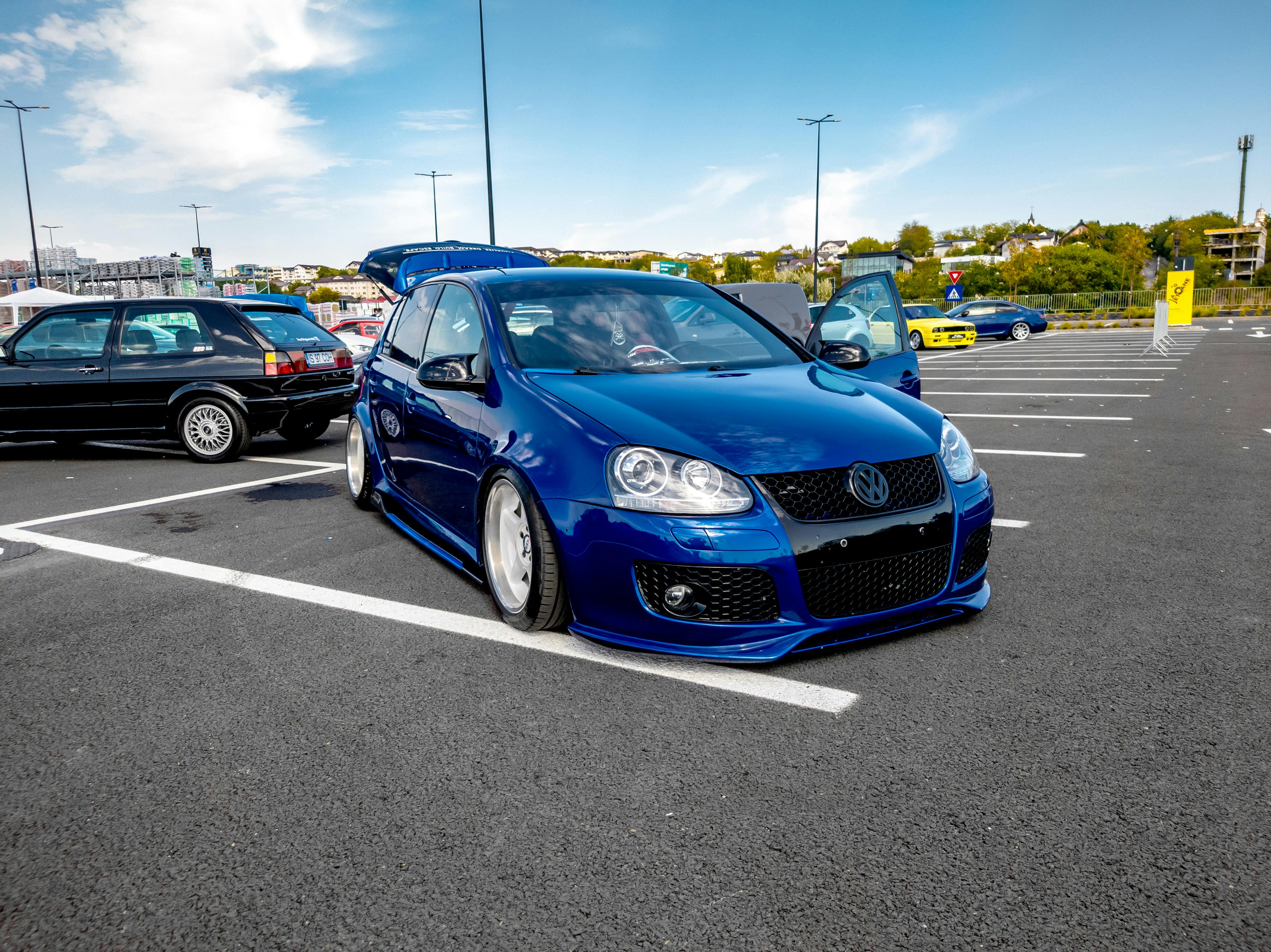 Gratis Una Volkswagen Golf blu personalizzata parcheggiata all'aperto insieme ad altre auto modificate in un ambiente urbano. Foto a disposizione