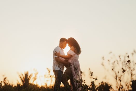 Couple embracing during a golden hour maternity shoot outdoors.