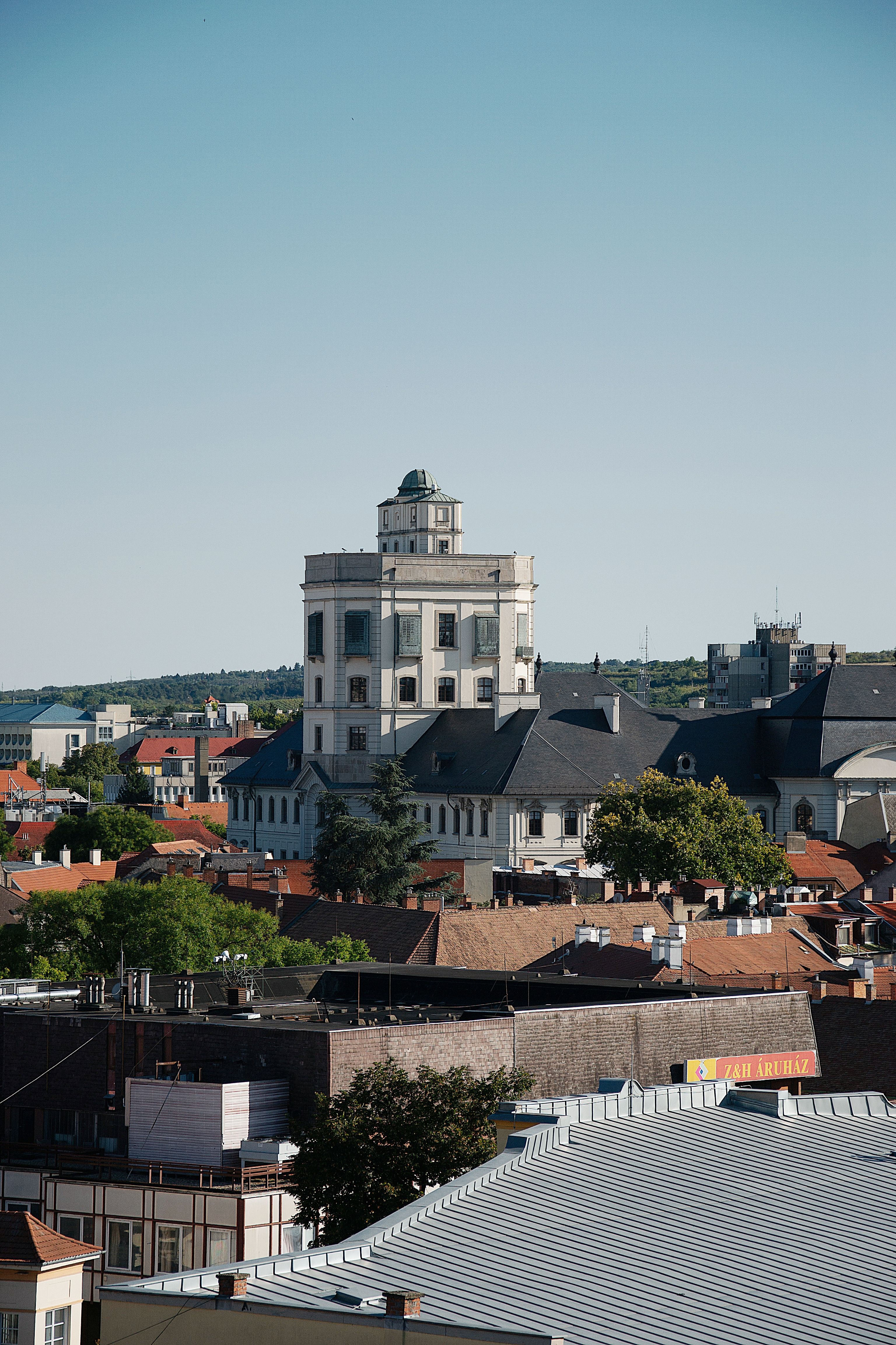 View of a historic building and rooftops in Veszprém, Hungary under a clear blue sky.
