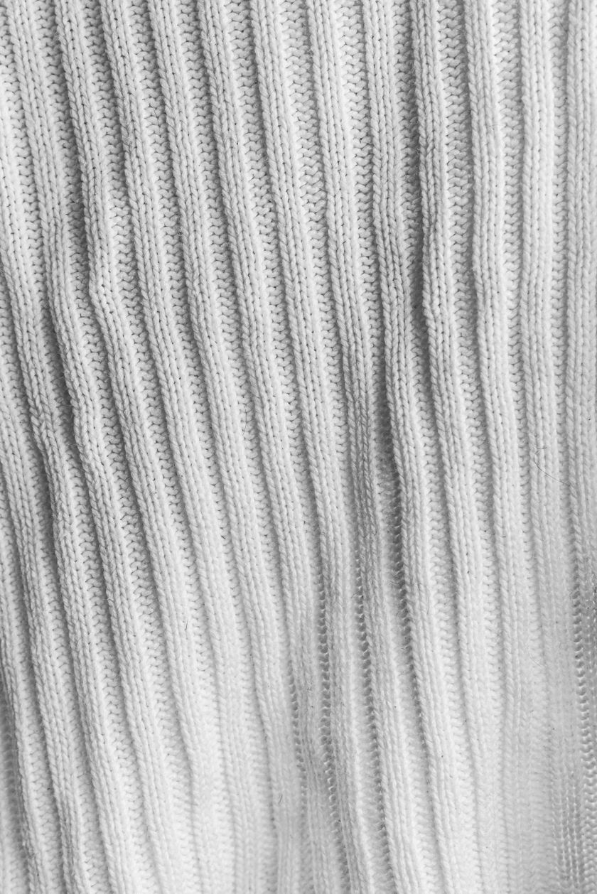 Close-up of a white rib-knit fabric, vertical rib columns running down the frame