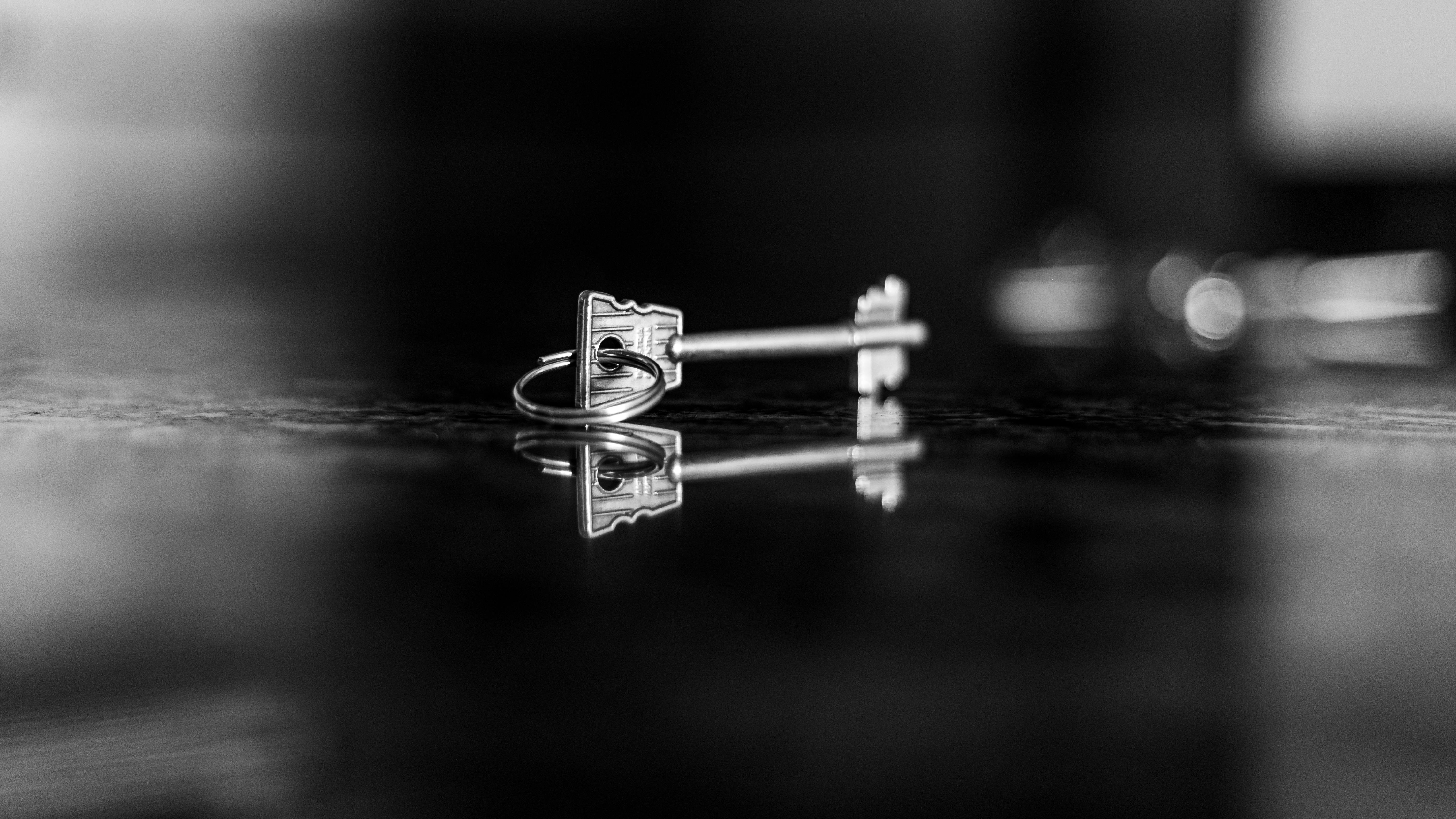 Free Artistic black and white photo capturing a key's reflection on a glossy surface, evoking mystery. Stock Photo