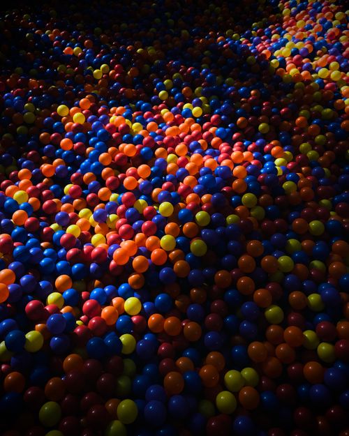 Free Vivid ball pit filled with colorful plastic balls illuminated by dynamic light and shadow contrast. Stock Photo
