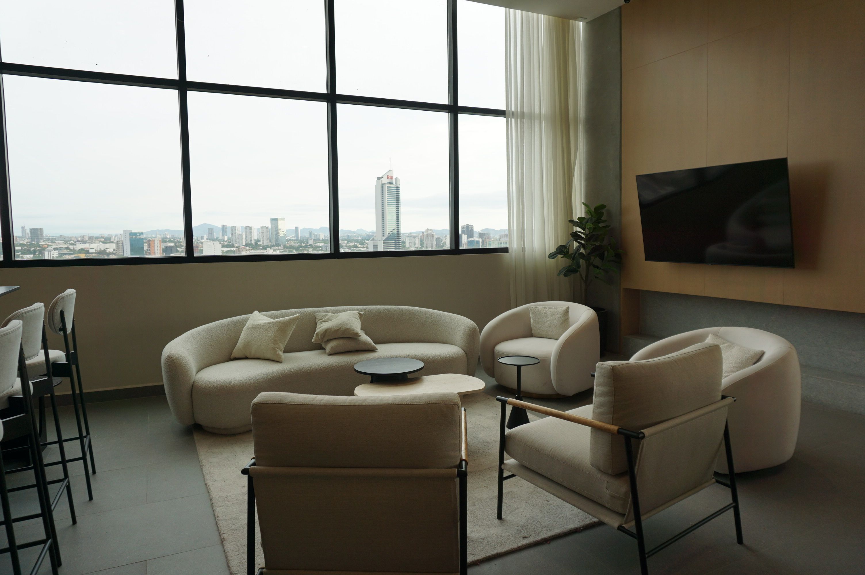 Young professional sitting in urban living room with side table, sofa, and city view