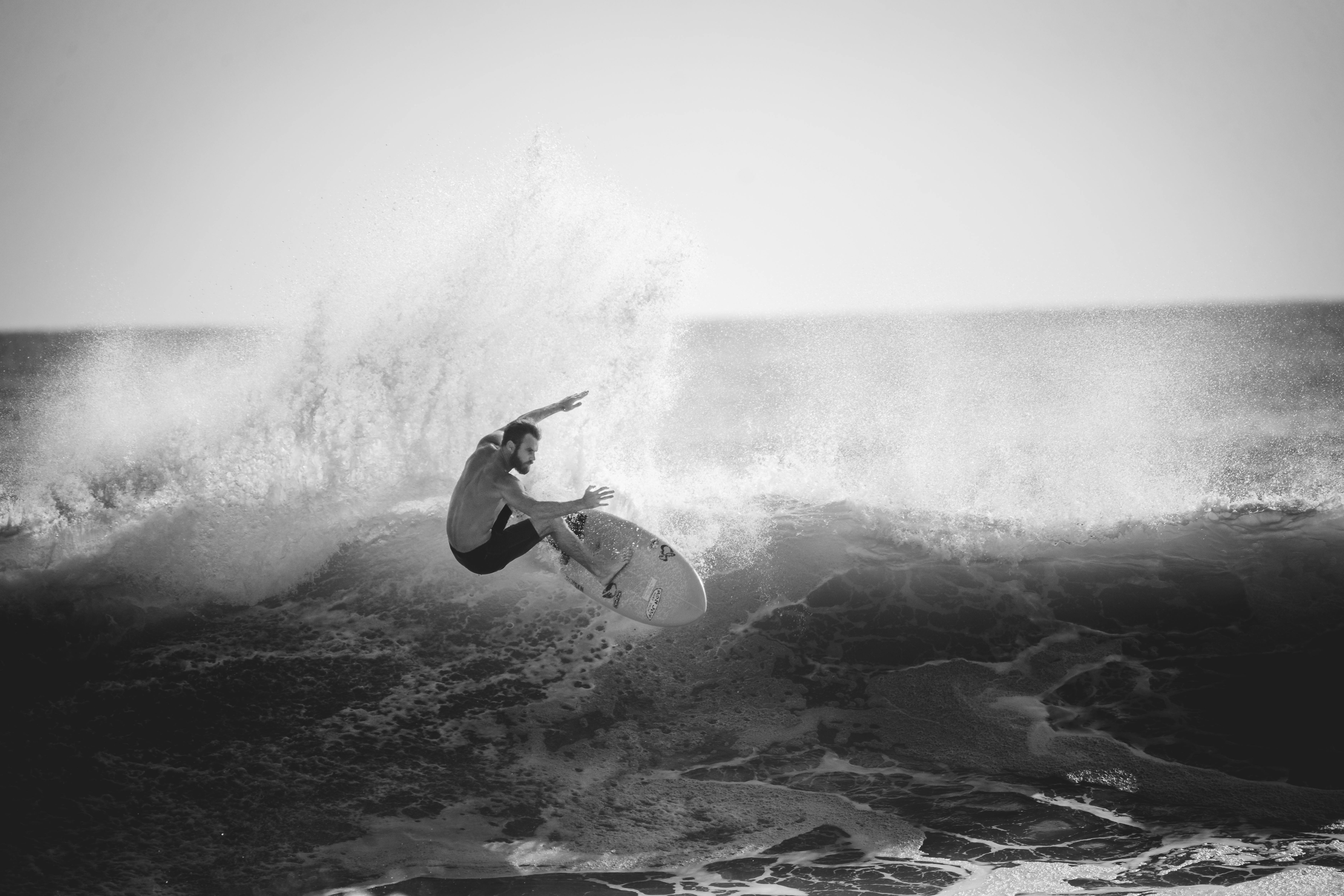 A monochrome action shot of a surfer mastering a large wave.