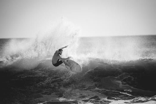 A monochrome action shot of a surfer mastering a large wave.