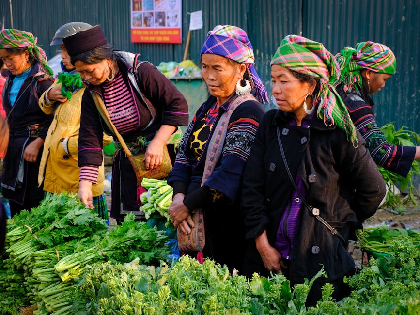Women in traditional attire shopping at a busy vegetable market in Lào Cai, Việt Nam.