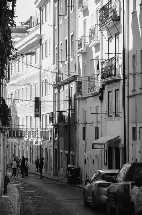Free A classic black and white photograph of a European street with people walking and parked cars. Stock Photo