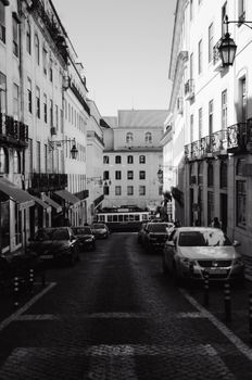 Monochrome view of a Lisbon street showcasing classic architecture and a tram.