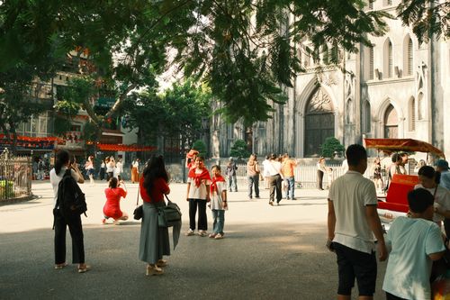 Free Tourists gather in front of an iconic historical church in Beijing, surrounded by trees and vibrant activity. Stock Photo