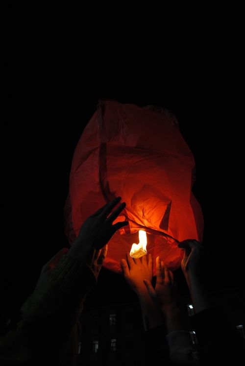 Free People launch a glowing sky lantern at a night festival, symbolizing hope and celebration. Stock Photo
