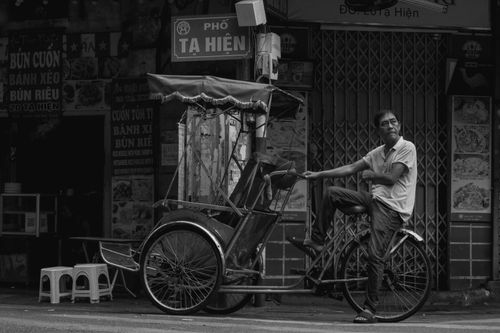 Free Captivating black and white photo of a cyclo rider on Tạ Hiện Street, Hanoi. Stock Photo