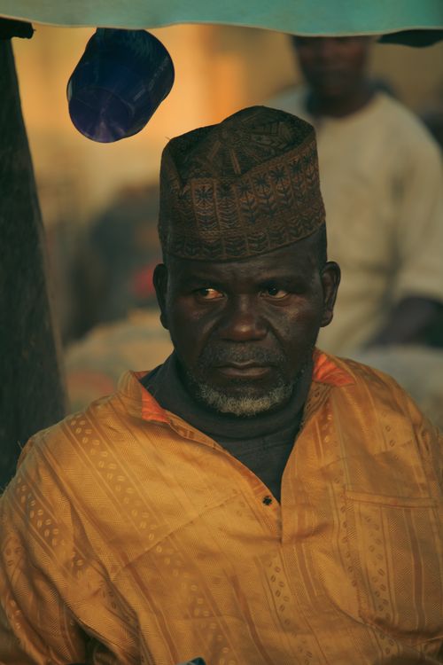 Free Elderly man wearing a traditional cap and yellow garment, captured in warm lighting. Stock Photo