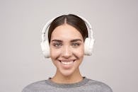 Woman Wearing Gray Crew-neck Shirt Using White Wireless Headphones Smiling