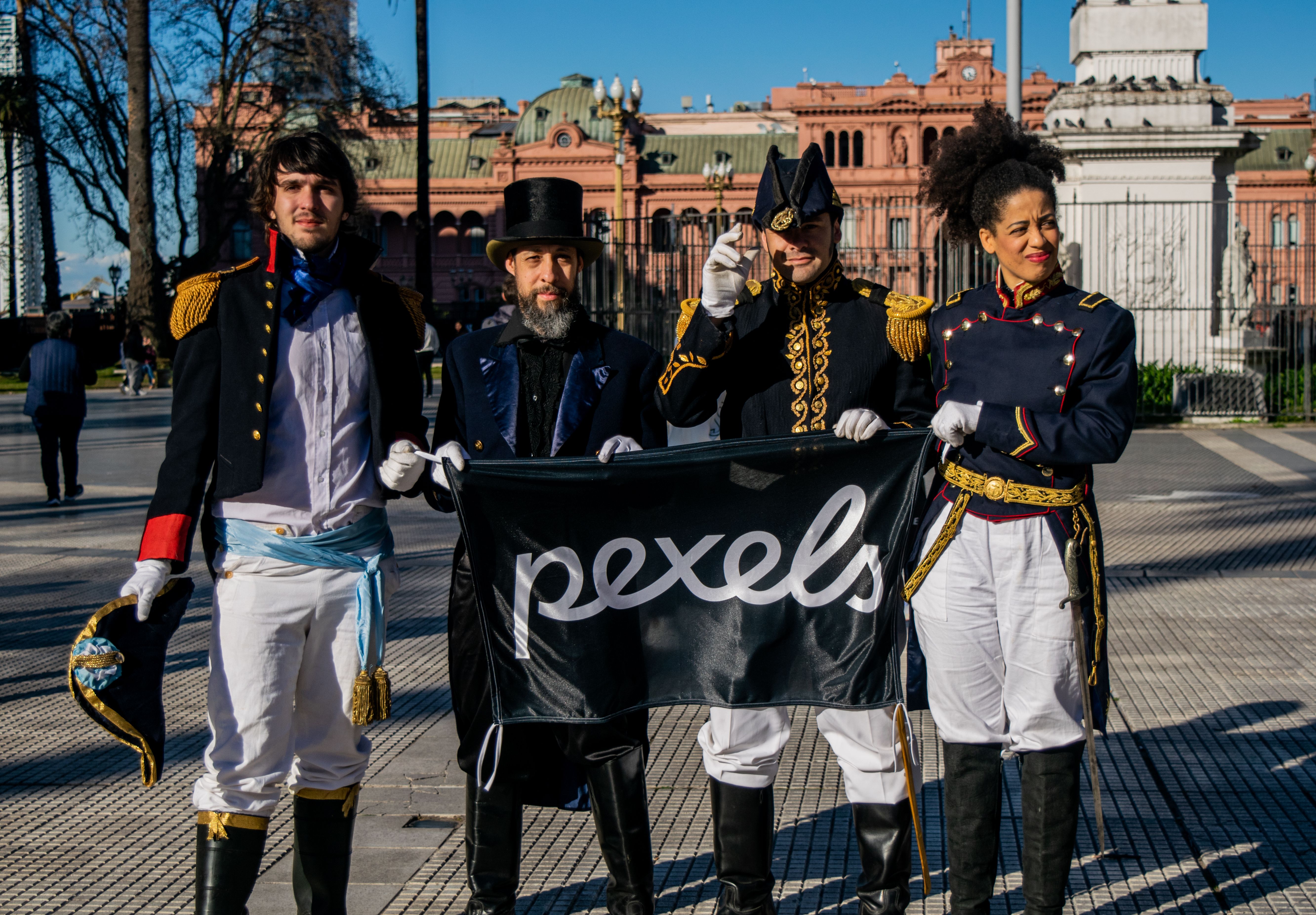Group of people in historical attire posing outside Casa Rosada, Buenos Aires.
